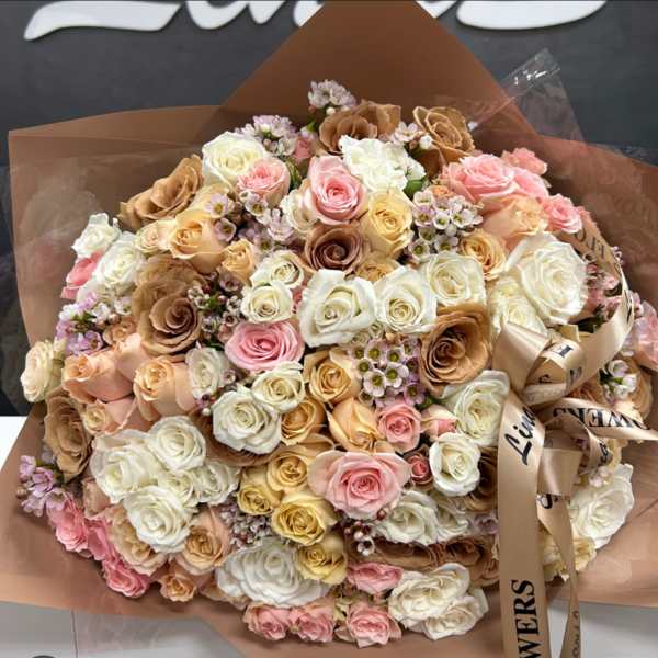 Large bouquet of pastel roses wrapped in brown paper with a satin ribbon