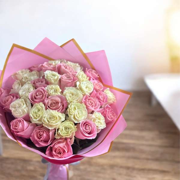 Bouquet of pink and cream roses wrapped in pink paper
