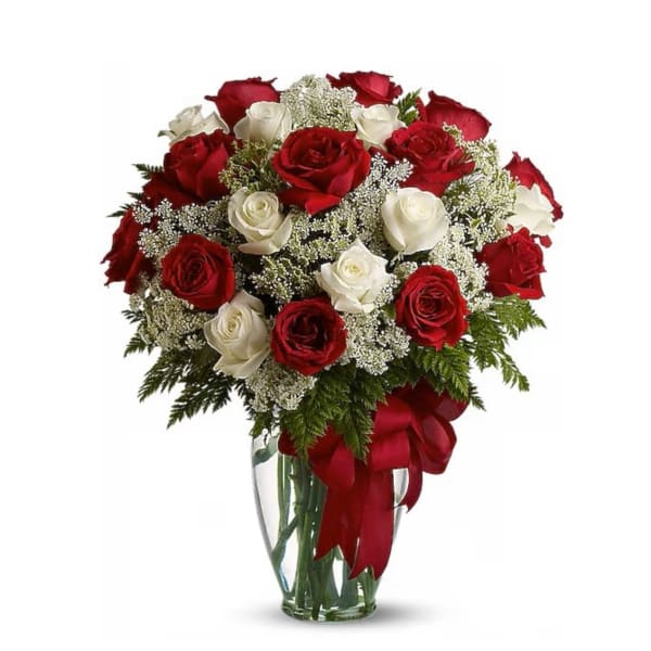 Bouquet of red and white roses in a clear glass vase with a red ribbon