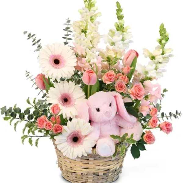 Pink and white flowers in a wicker basket with a plush bunny