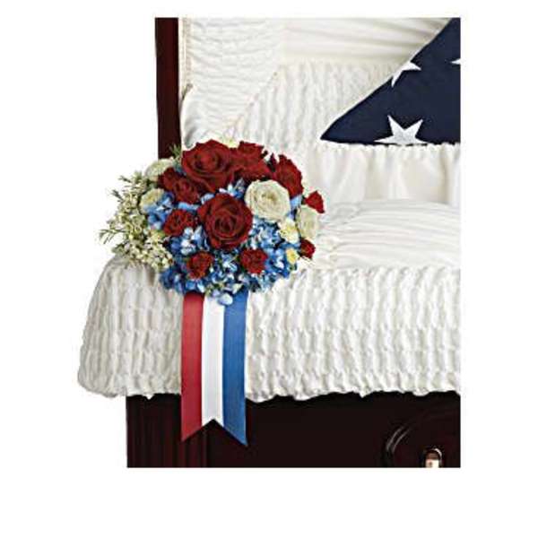 Red, white, and blue floral spray on a white-draped casket