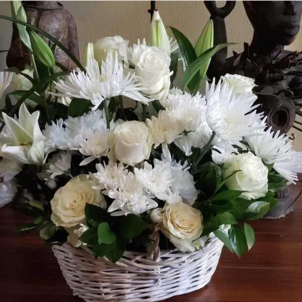 White roses and daisy-like flowers in a wicker basket