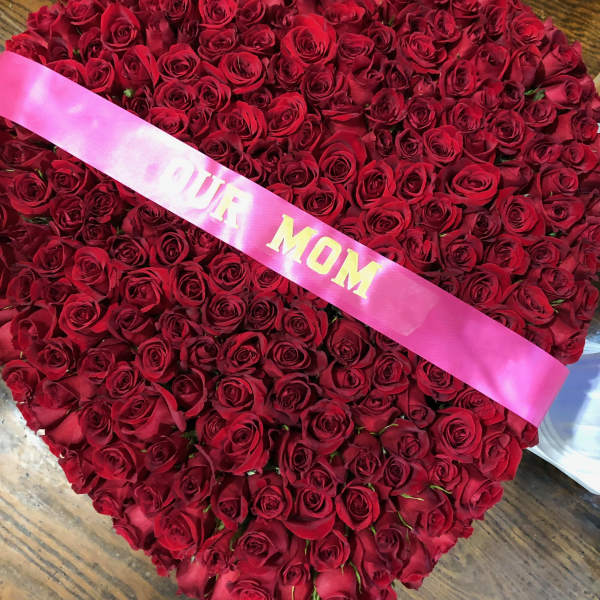 Heart-shaped bouquet of red roses with a pink ribbon