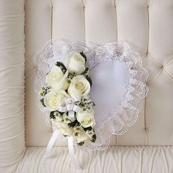 Heart-shaped white lace pillow with white roses and small daisies on one side