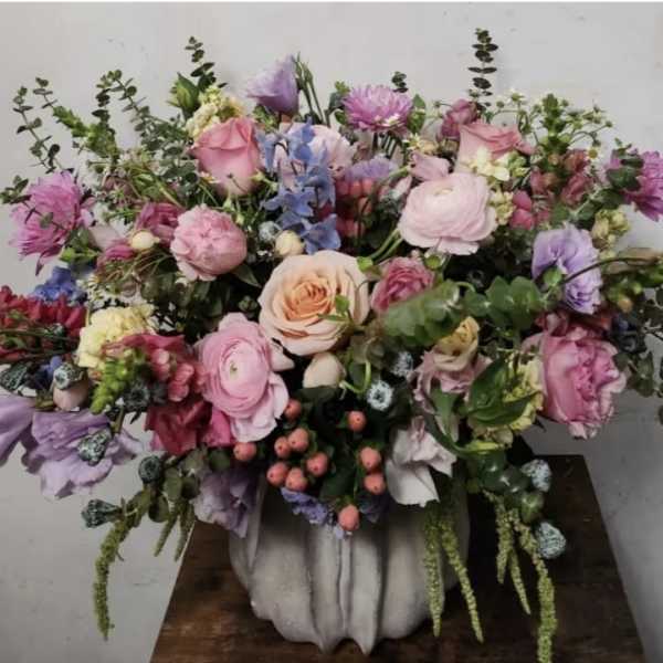 Large pastel bouquet in a white vase with pink, lavender, and peach flowers