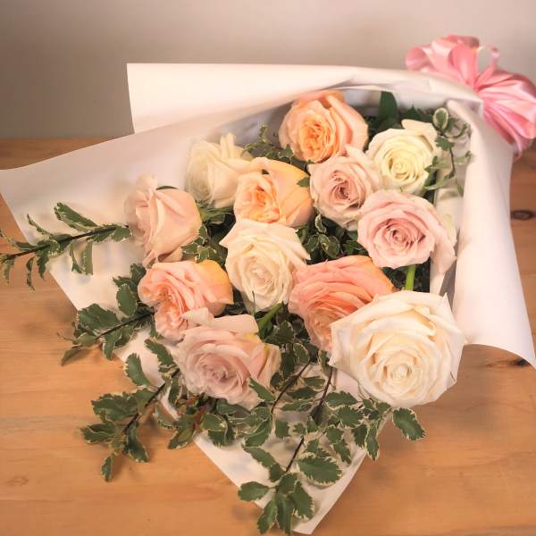 Bouquet of pale pink and cream roses wrapped in white paper