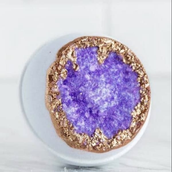 Purple geode-style decorative stone with a gold edge on a white surface