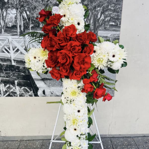 Red roses and white daisies arranged on a standing cross display
