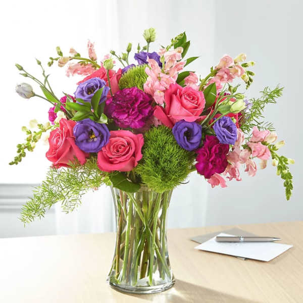Mixed bouquet of pink and purple flowers in a clear glass vase