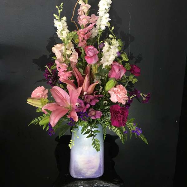 Tall pink and white floral arrangement in a pastel vase