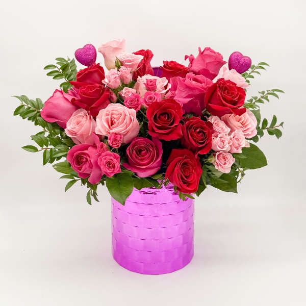 Pink and red roses in a bright pink vase with glitter heart picks