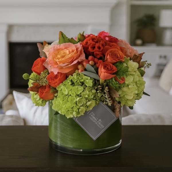 Orange and peach roses with green hydrangeas in a glass vase
