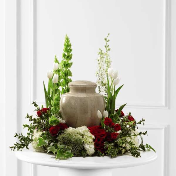 Red roses and white tulips arranged around a beige urn