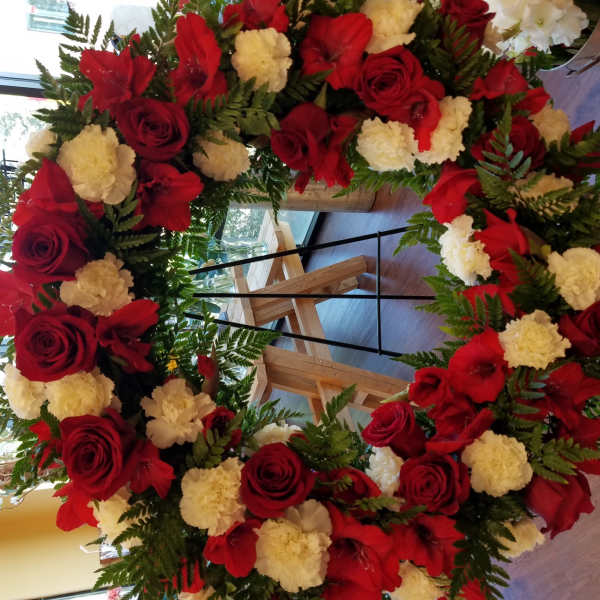 Large red and white floral wreath on a stand