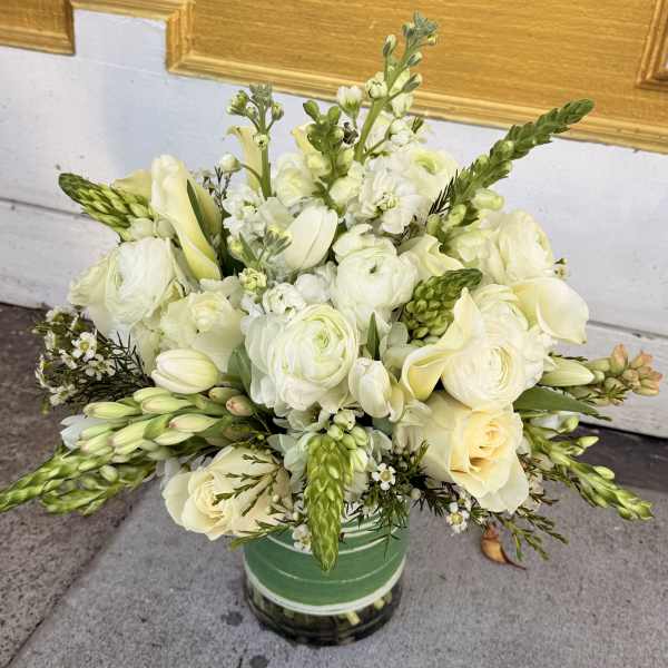 White and pale yellow floral arrangement in a green vase