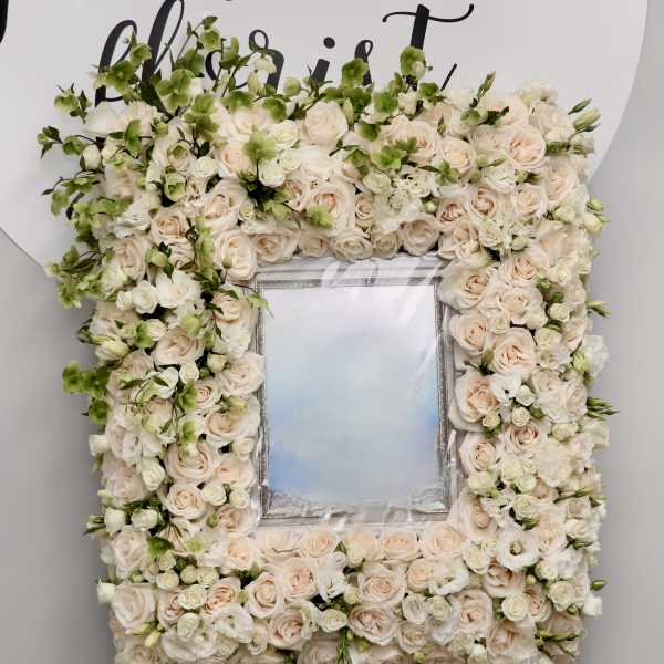 Floral frame of pale roses and white blooms around a mirror