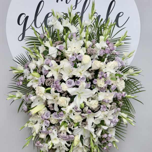Large white and lavender funeral spray on an easel