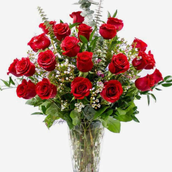 Tall arrangement of red roses with filler blooms in a clear glass vase