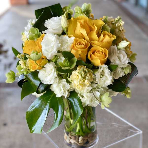 Yellow and white roses arranged in a clear glass vase