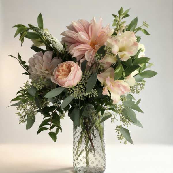 Pink and cream flowers in a clear textured glass vase