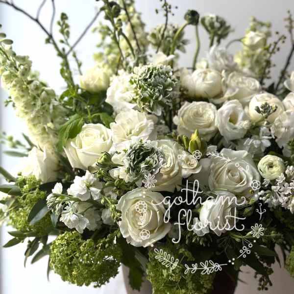 White roses and ranunculus arranged in a dark vase