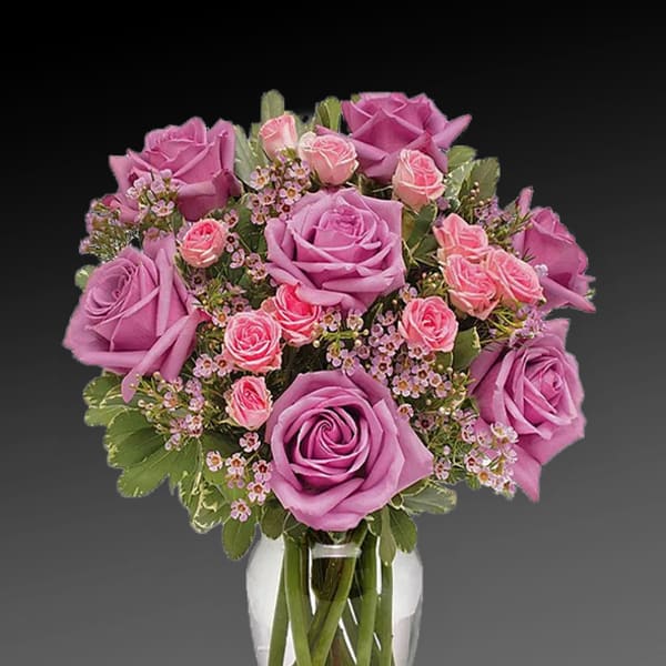 Pink and lavender roses arranged in a clear glass vase