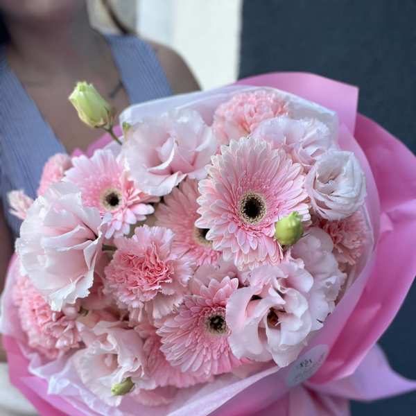 Pink bouquet of gerbera daisies, carnations, and lisianthus wrapped in pink paper