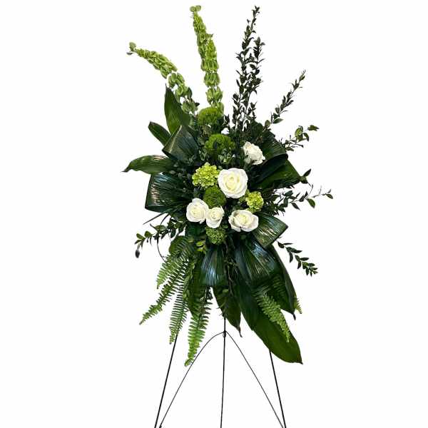 Tall standing floral spray with white roses and green foliage on an easel