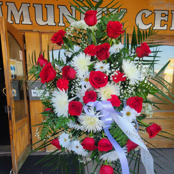 Standing floral spray with red roses and white daisies on a ribboned easel