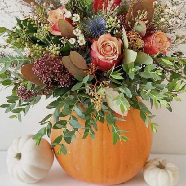 Floral arrangement in a pumpkin with pink and peach roses
