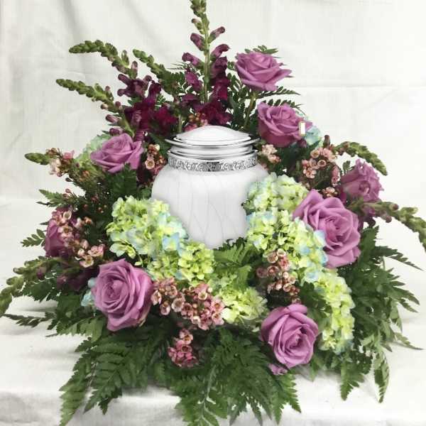 Lavender roses and hydrangeas arranged around a white urn
