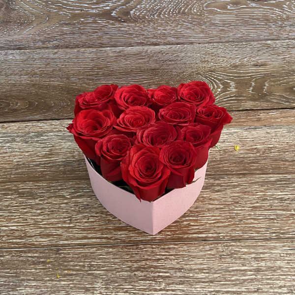 Heart-shaped box of red roses on a wooden surface
