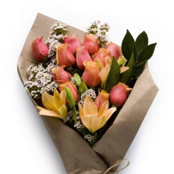 Bouquet of pink roses and peach lilies with white filler flowers wrapped in brown paper