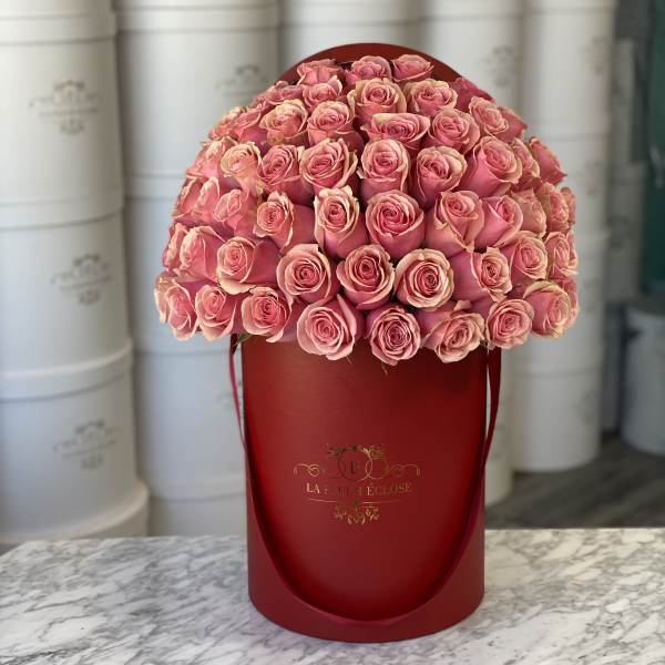 Pink roses arranged in a red hatbox