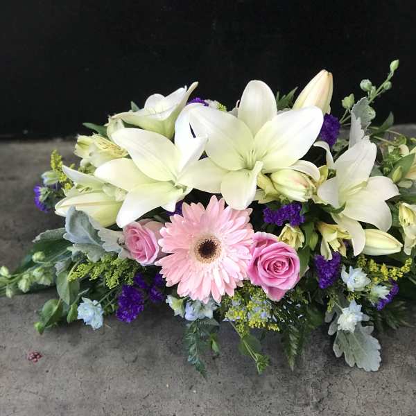 Low floral arrangement with white lilies, pink gerbera daisy, and pink roses