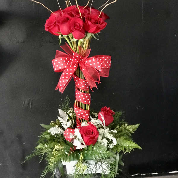 Tall bouquet of red roses with a polka-dot ribbon on a white base