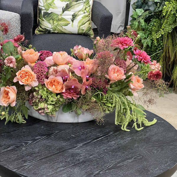 Low floral centerpiece with pink and peach blooms in a shallow white bowl