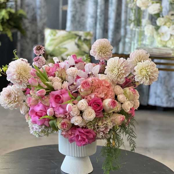 Pink and white floral arrangement in a ribbed pedestal vase