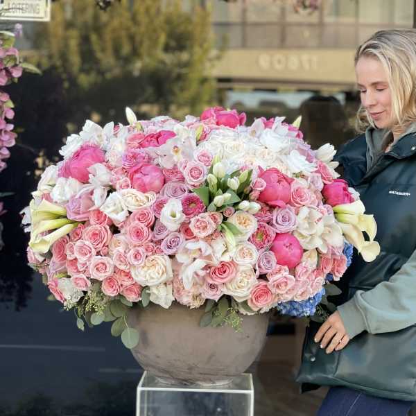 Large pink and white floral arrangement in a round vase