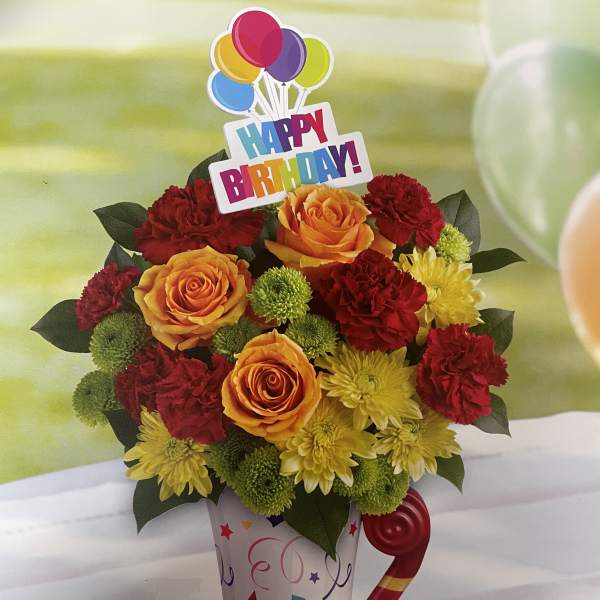 Birthday bouquet of roses, carnations, and mums in a decorated mug
