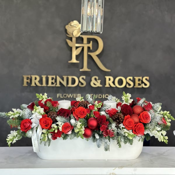 Red rose centerpiece in a white rectangular vase with candles and pinecones