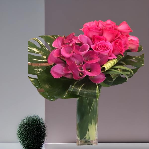 Pink roses and calla lilies in a tall glass vase