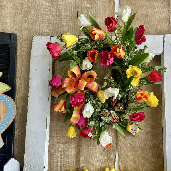 Colorful tulip wreath with a plaid bow on a white frame