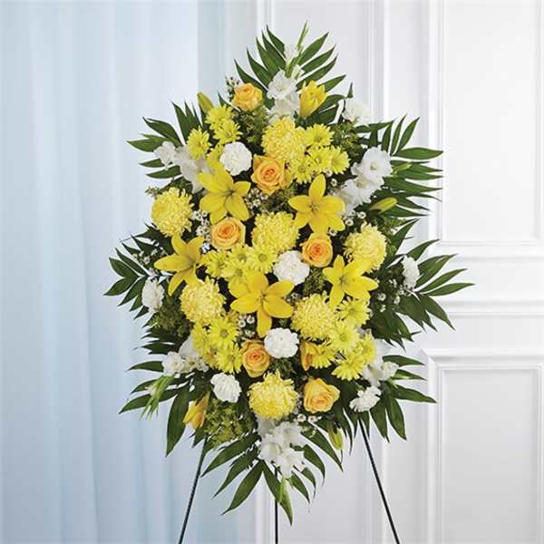 Tall yellow and white standing spray of lilies, roses, and carnations on an easel