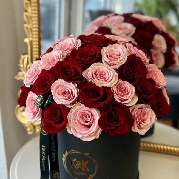 Pink and red roses arranged in a black hat box