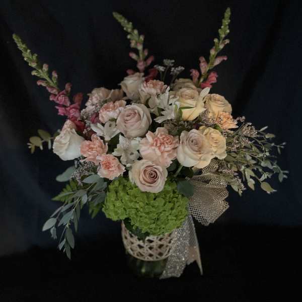 Bouquet of pale roses and pink carnations in a decorative vase