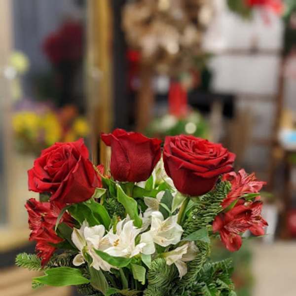 Red roses and white flowers arranged in a glass jar vase