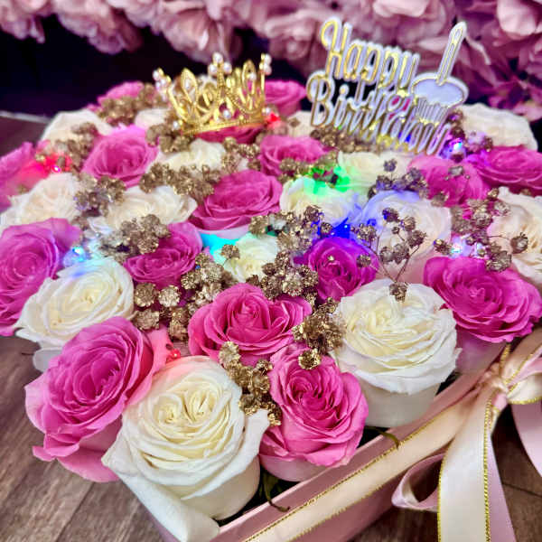 Pink and white roses in a gift box with a birthday topper and crown