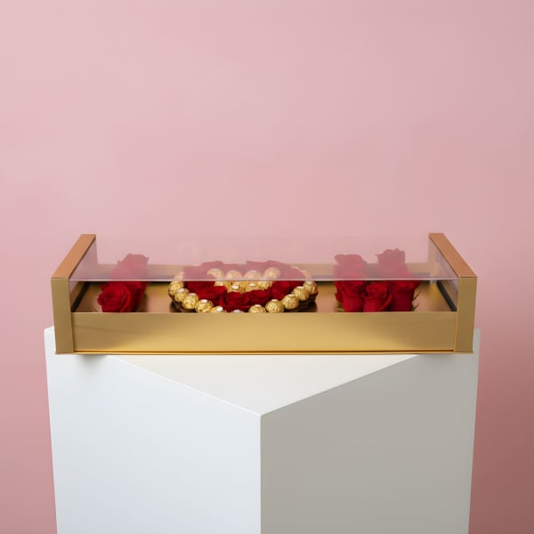 Red roses arranged in a gold box with a clear lid
