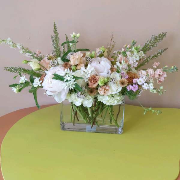 Pastel mixed flower arrangement in a clear rectangular vase
